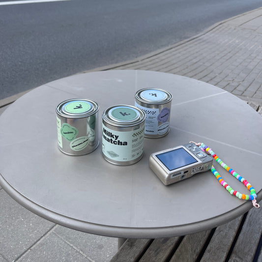 Three cans and a digital device on a round metal table outdoors.