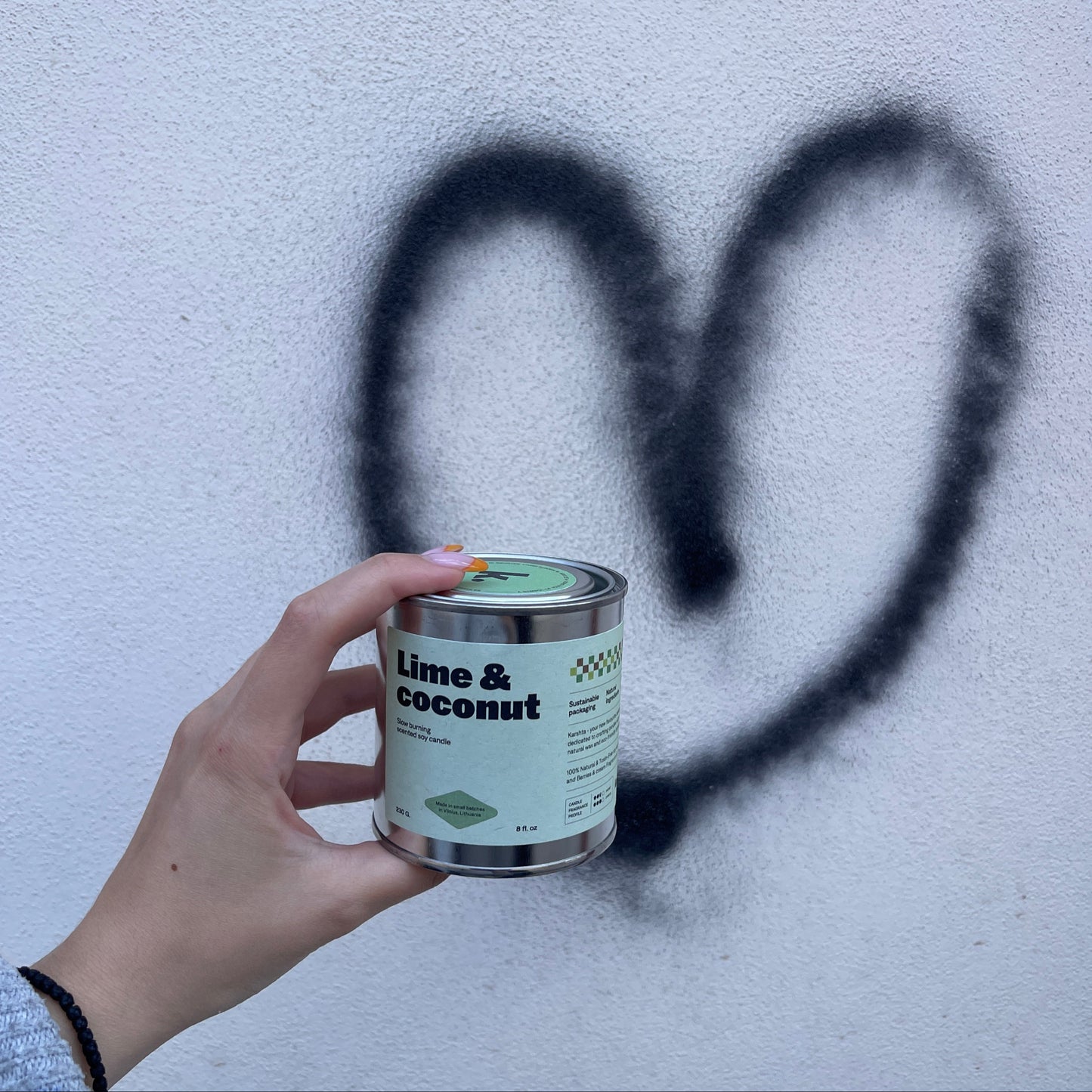Hand holding a can of 'Lime & Coconut' against a light background with graffiti.
