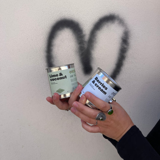 Two cans of 'Lime & Coconut' paint being held above a gray surface with a black spray pattern.