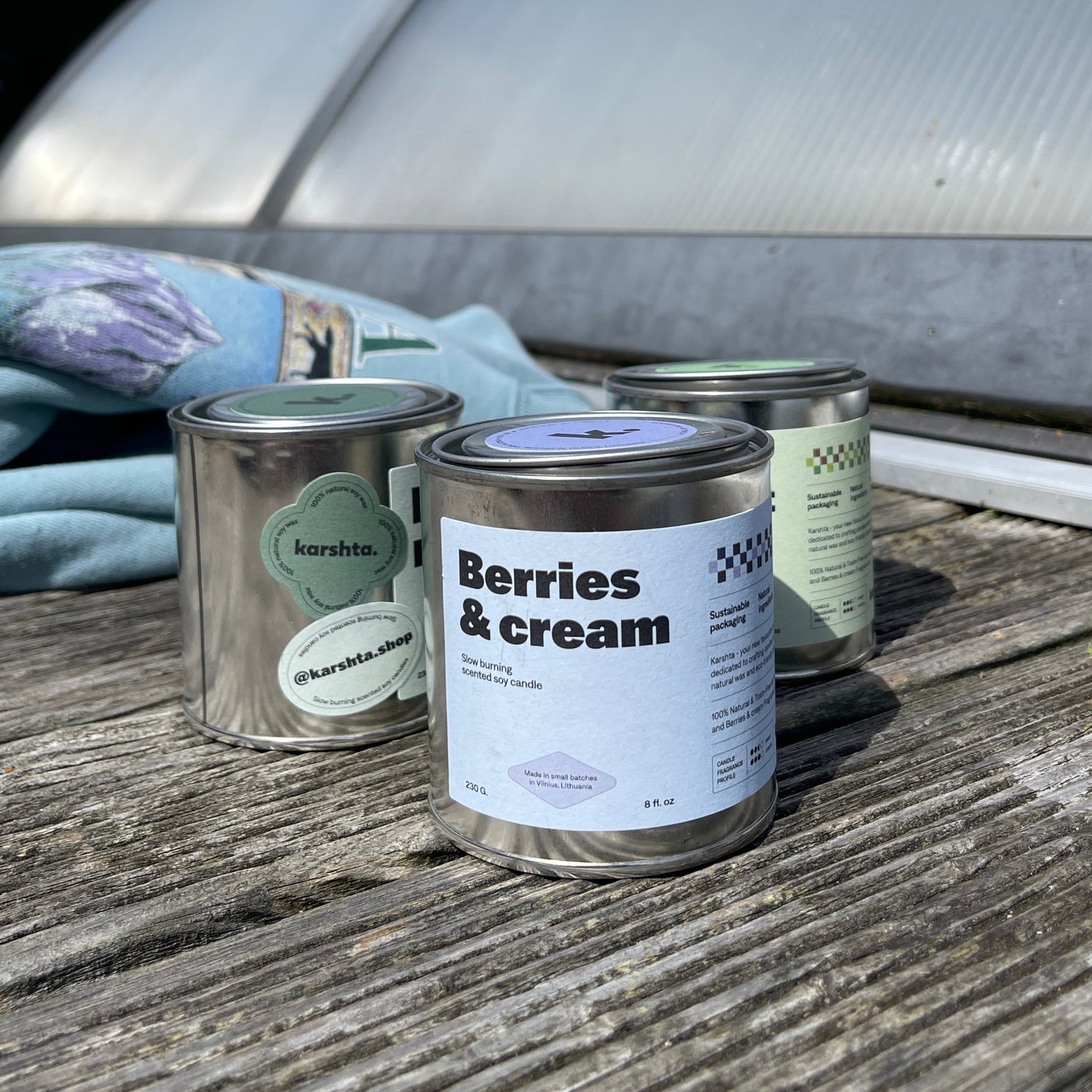 Two cans of 'Berries & Cream' paint on a wooden surface with a snowy landscape in the background.