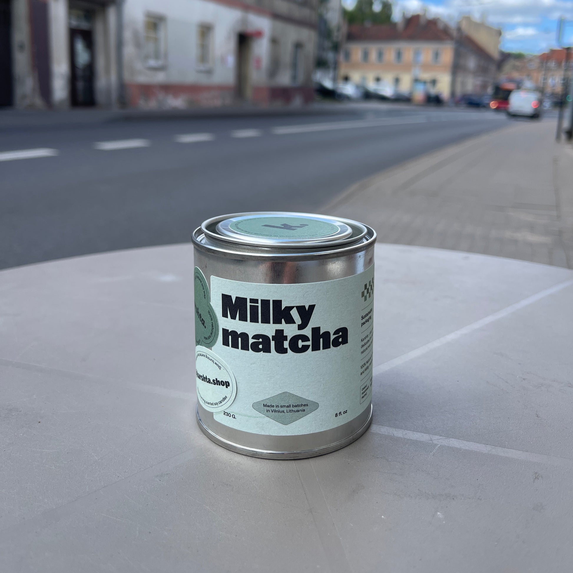 Can of Milky Matcha on a concrete surface with a blurred street scene in the background